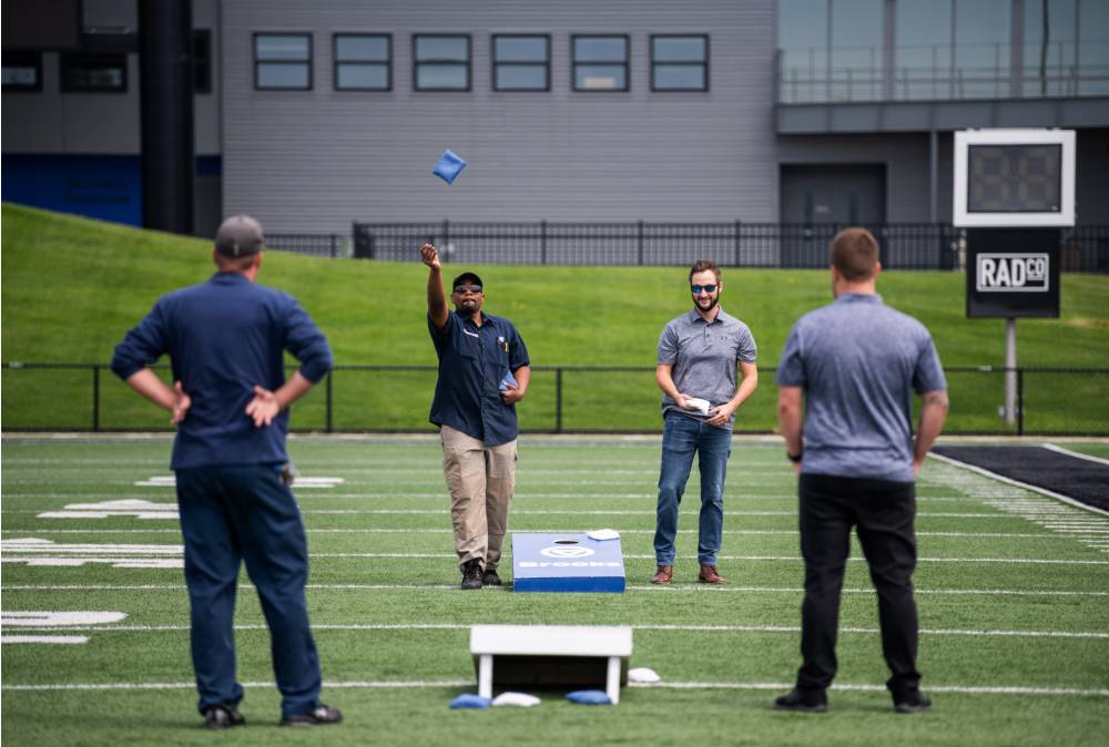 A bag being launched in the air in a cornhole match between two Facilities teams